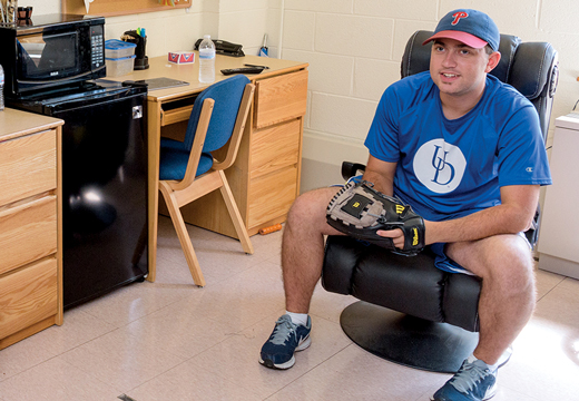 Image of Nick Godwin in his residence hall room with a baseball cap and ball