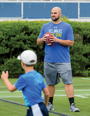 Gino Gradkowski with a group of children on UD's football field