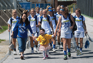 UD women's lacrosse players walking with child