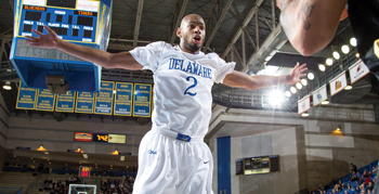 an image of a UD men's basketball player jumping with his arms out