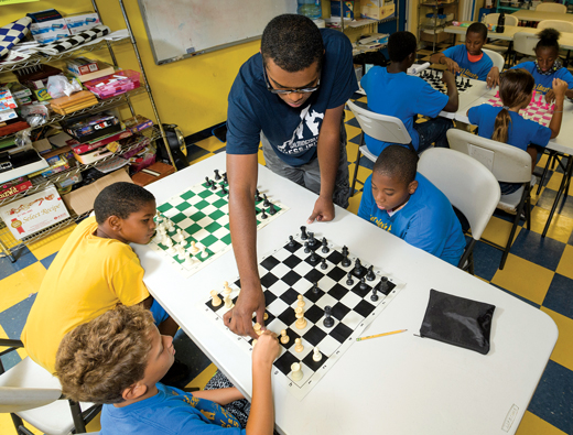 Image of Johnny Means teaching young school age children to play chess for the Wilmington Urban Chess Initiative